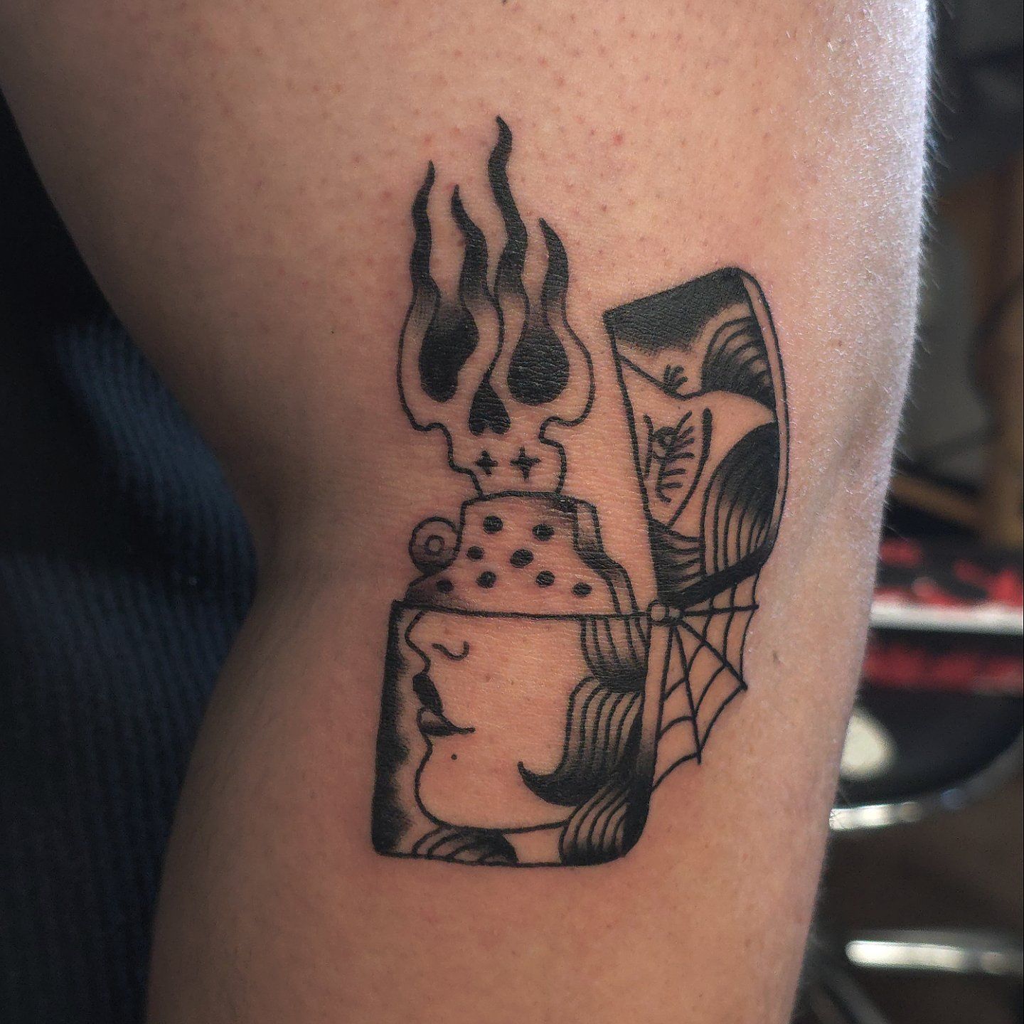 A tattoo of a woman's face in a lighter with flames coming out of it