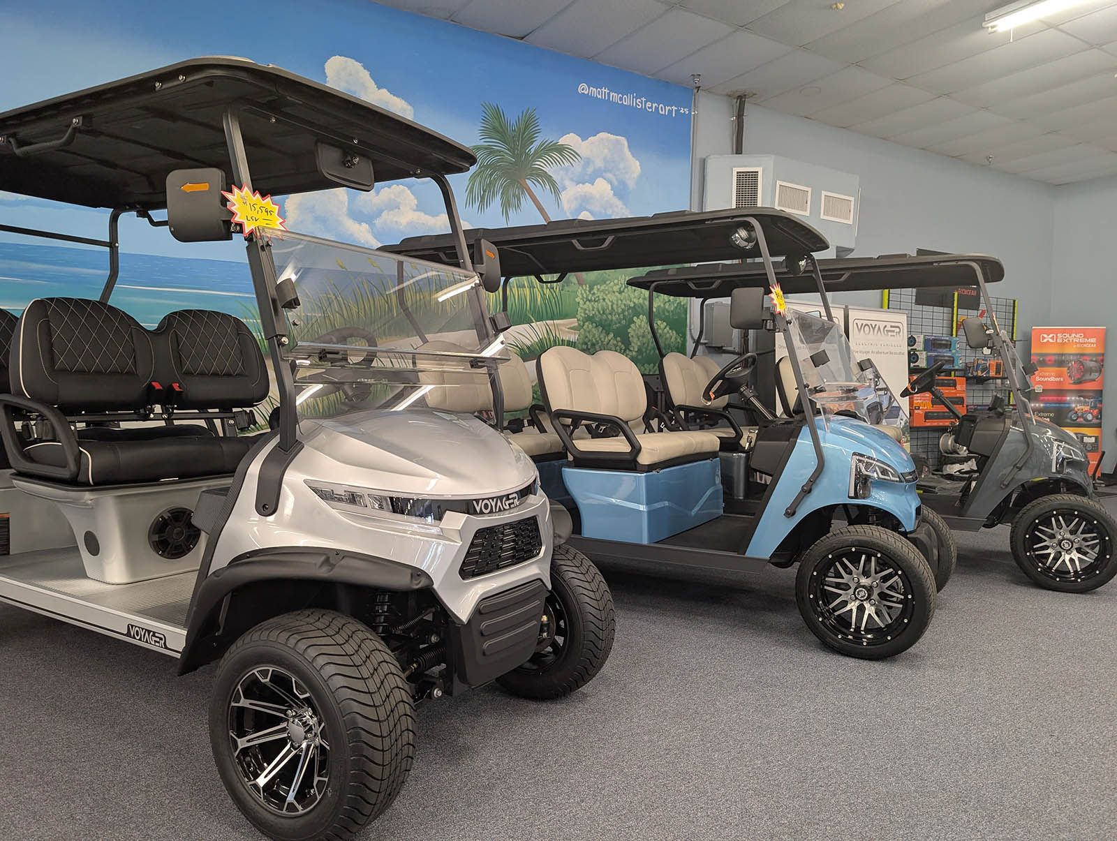 Golf carts in showroom with ocean mural backdrop