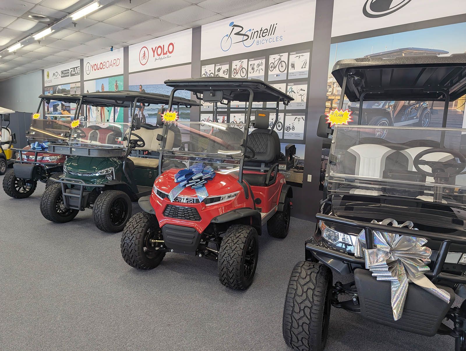 Several golf carts on display in a store, with various colors and features
