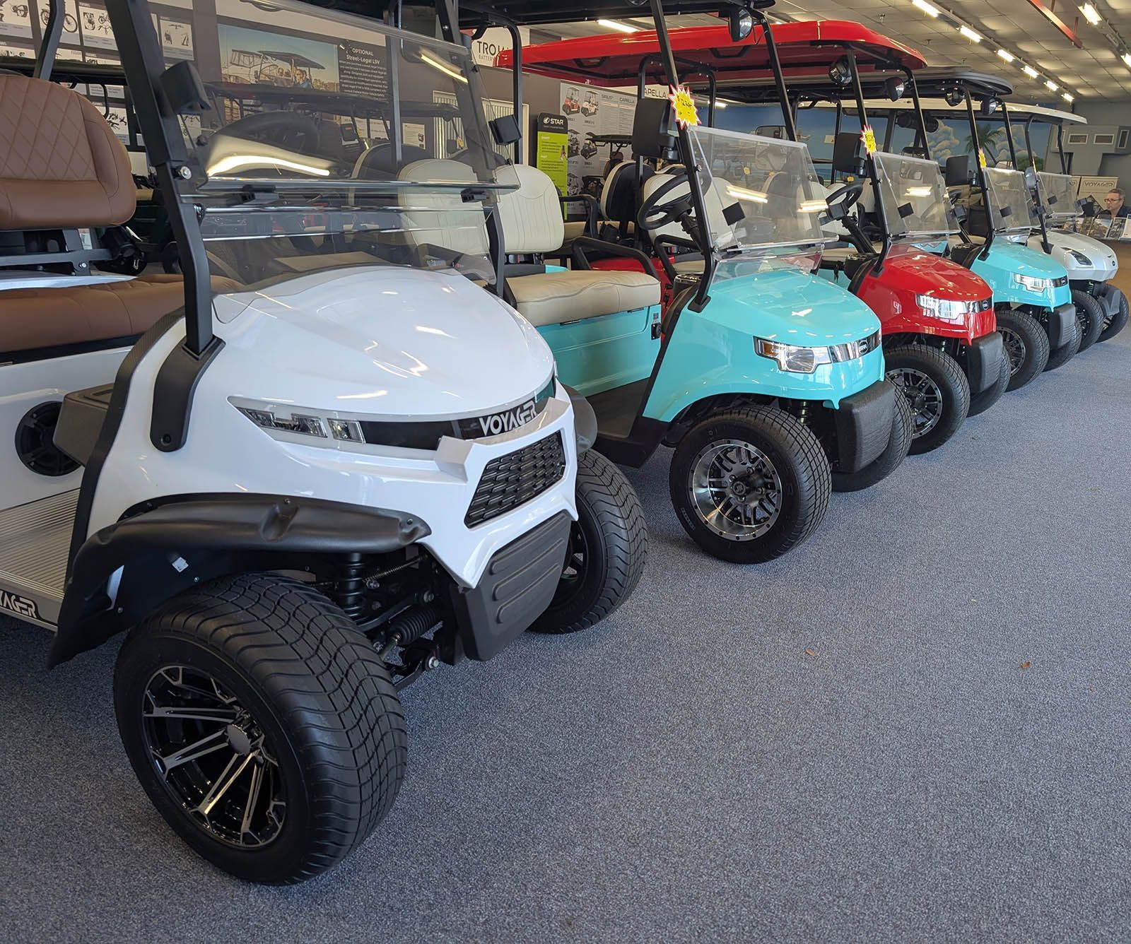 Golf carts of various colors lined up indoors