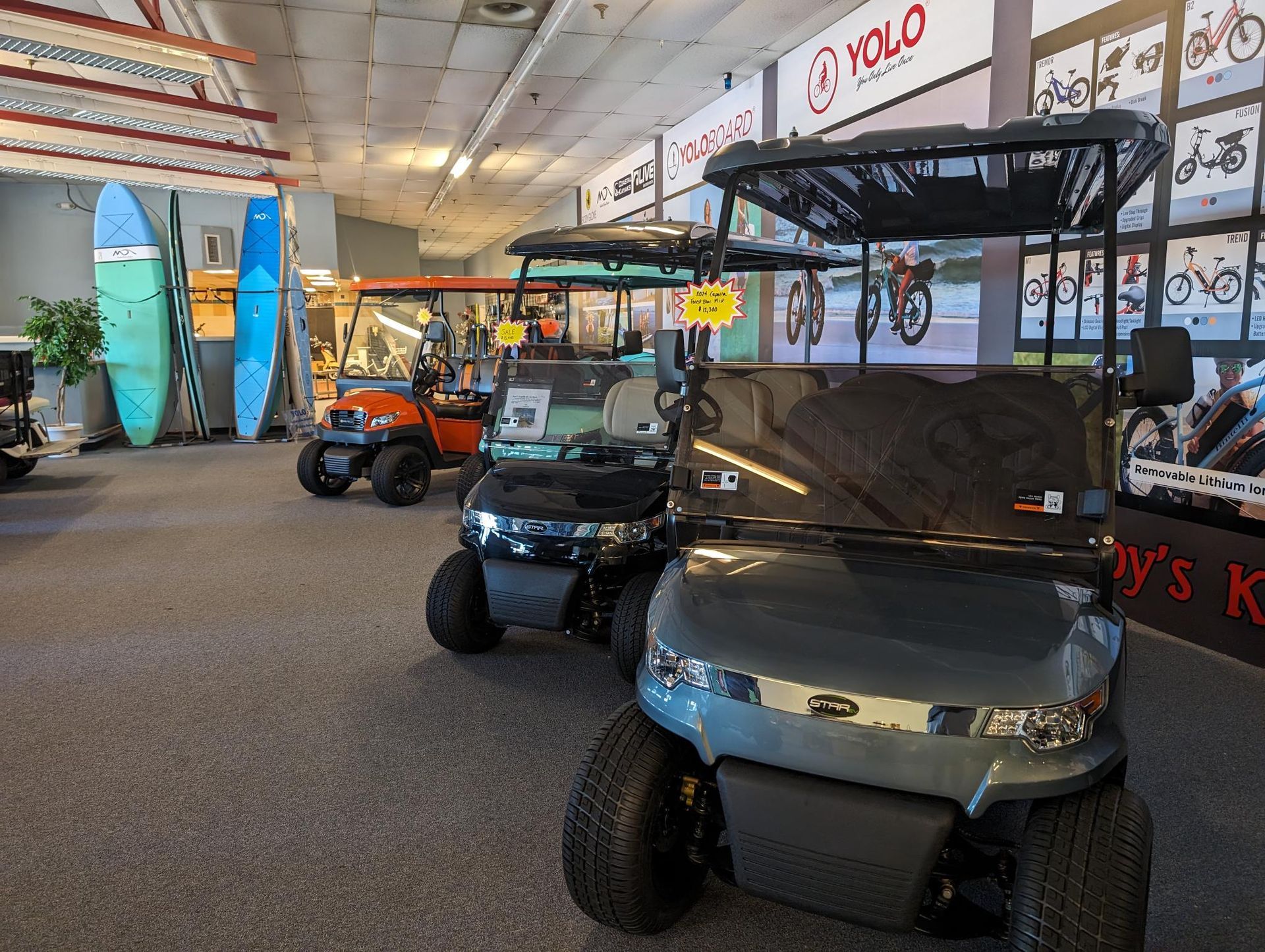 A showroom filled with golf carts and surfboards.