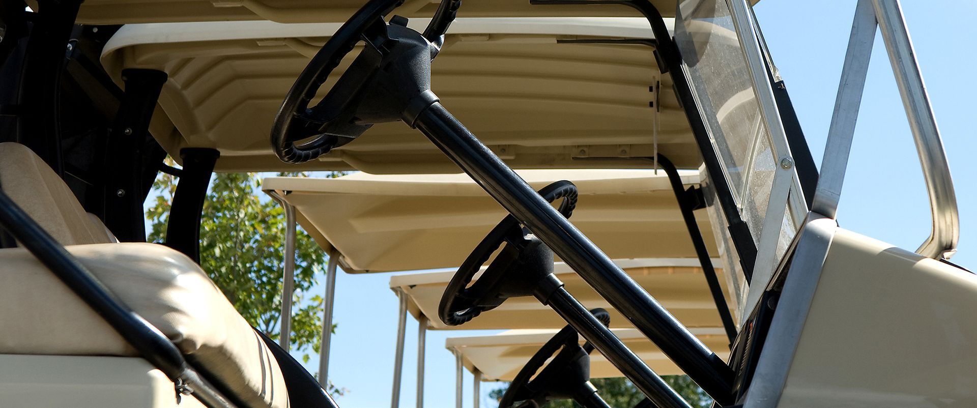 A row of golf carts are parked next to each other