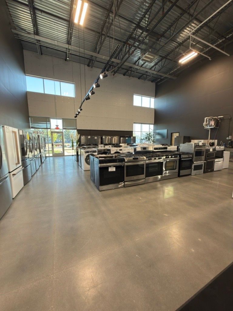 Empty modern industrial showroom with tables, track lighting, high ceiling, and large windows