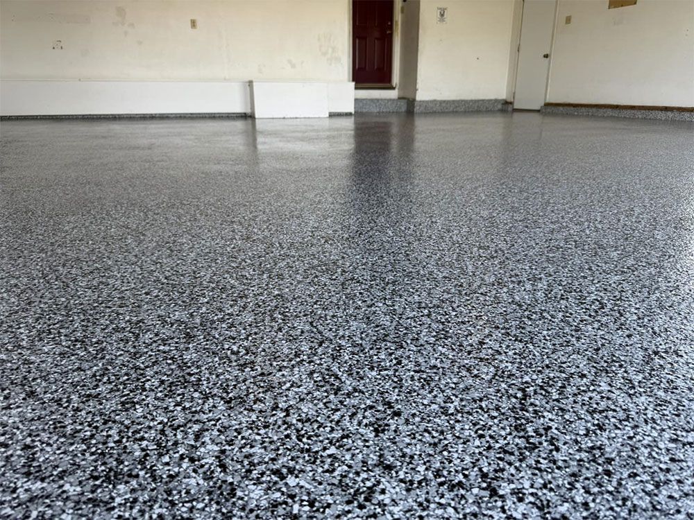 Speckled gray epoxy floor in an empty room with white walls and a door.