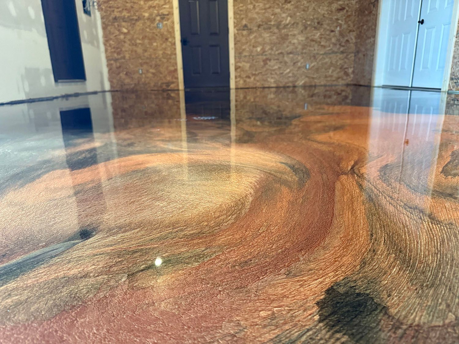 Polished concrete floor with colorful swirling reflections in an unfinished room.