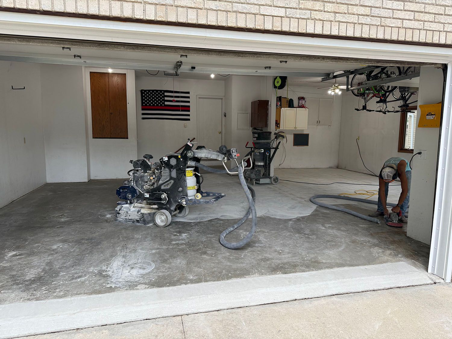 Garage interior with a motorcycle and tools on a concrete floor, American flag on the wall.