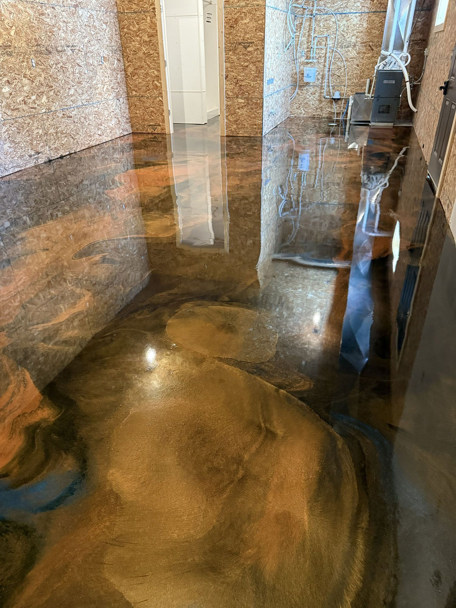 Flooded stone floor with reflective standing water in an indoor hallway.