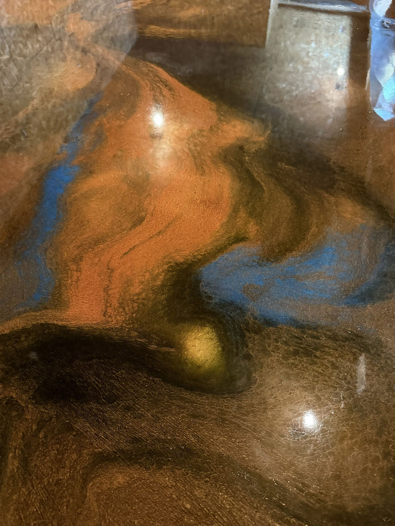 Abstract close-up of brown and blue marbled surface with reflective highlights.