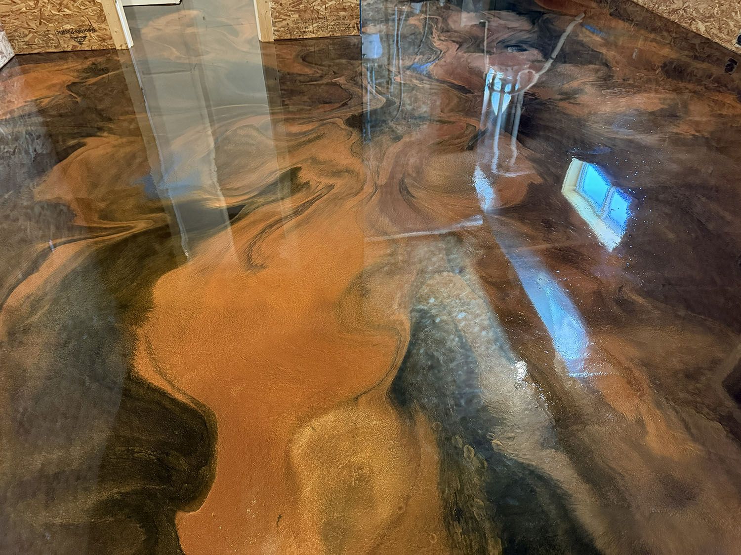 Close-up of a glossy brown and black marbled tabletop with reflections of a window and room light.