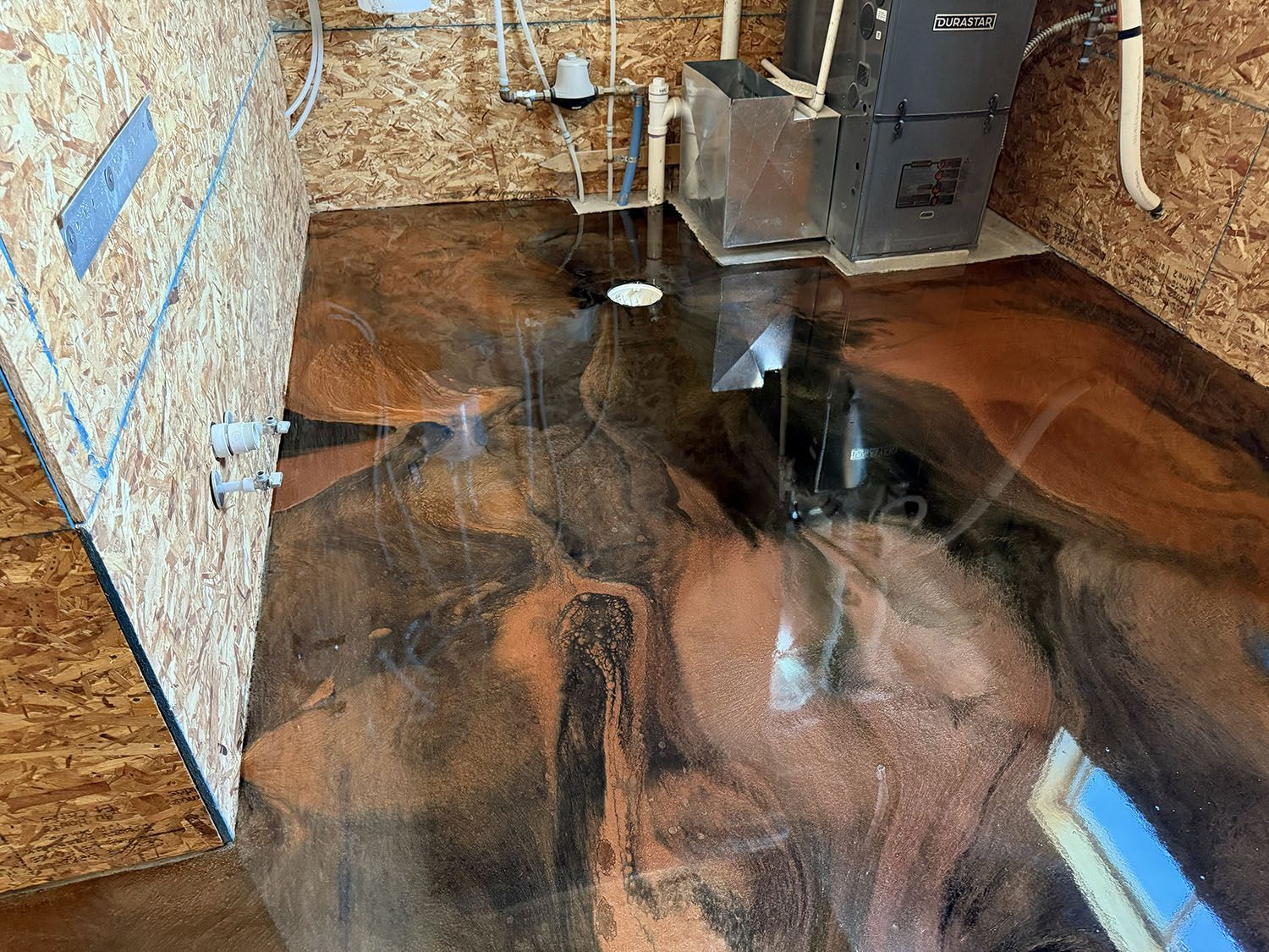 Flooded basement with standing water, reflecting exposed insulation, pipes, and a water heater.
