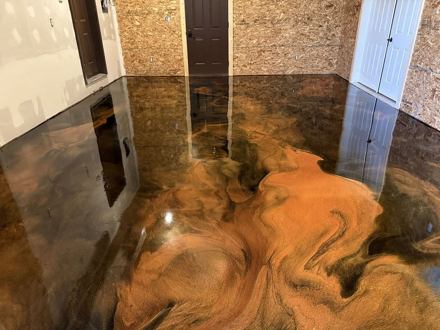 Flooded room with glossy brown-black water and reflections of doors and walls.
