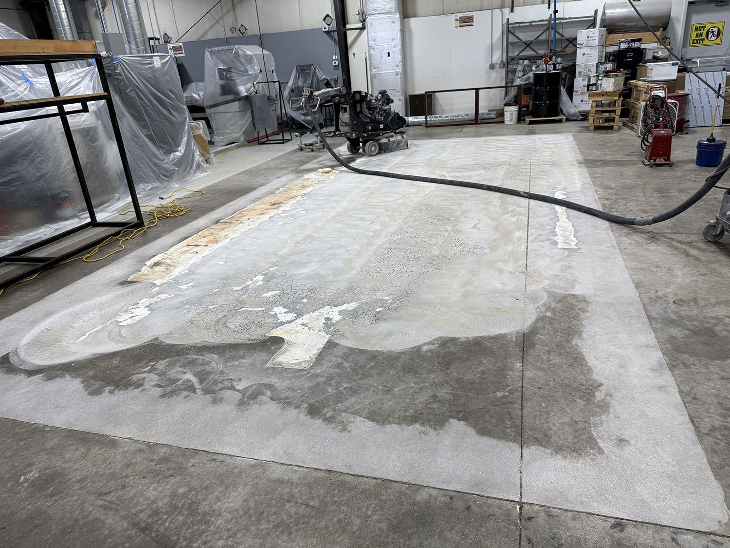 Industrial warehouse floor with large patched concrete slab and equipment in the background.