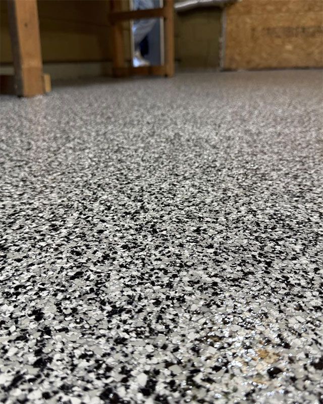 Low-angle view of speckled gray floor in a room with wooden furniture in the background