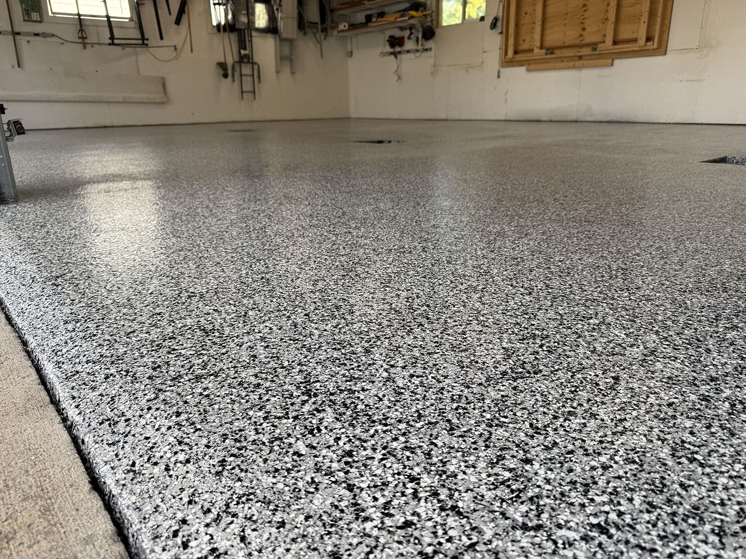 Freshly coated speckled epoxy floor in a garage or basement workspace.