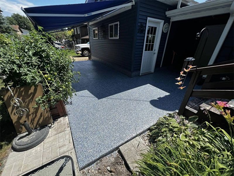 Blue-gray patio beside a dark house, with an open door and potted plants in the foreground.