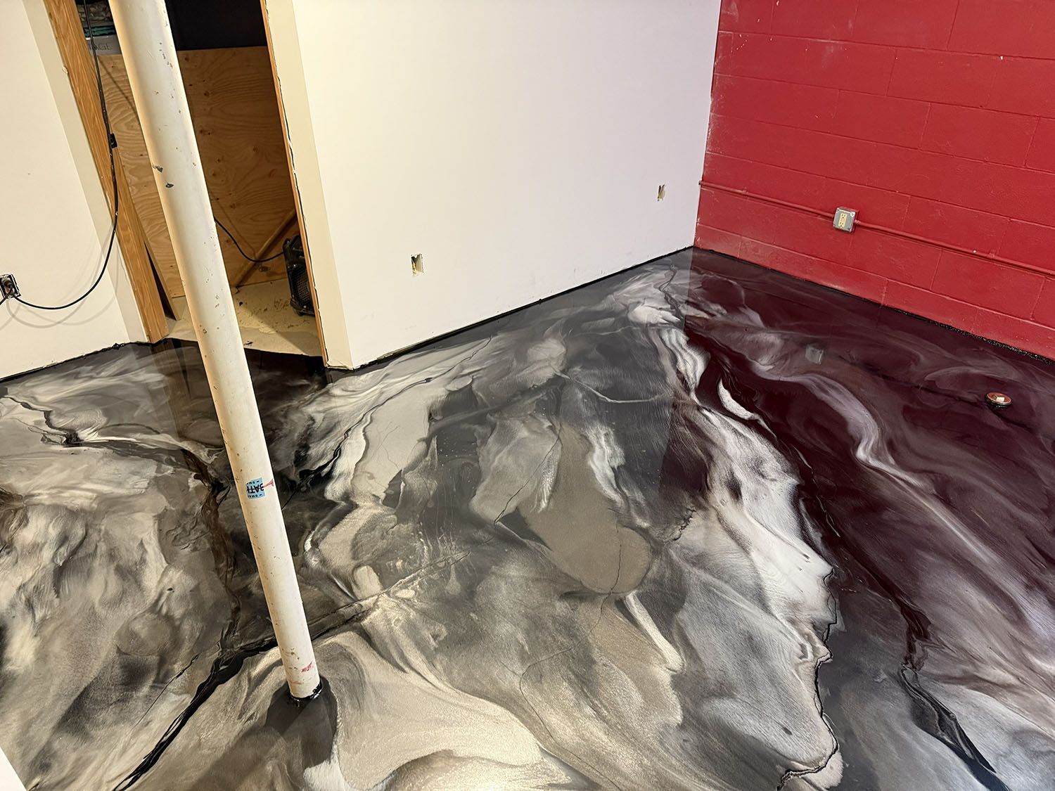 Black-and-gray marbled floor in a room with a red wall and open doorway, showing a white pole in the foreground.