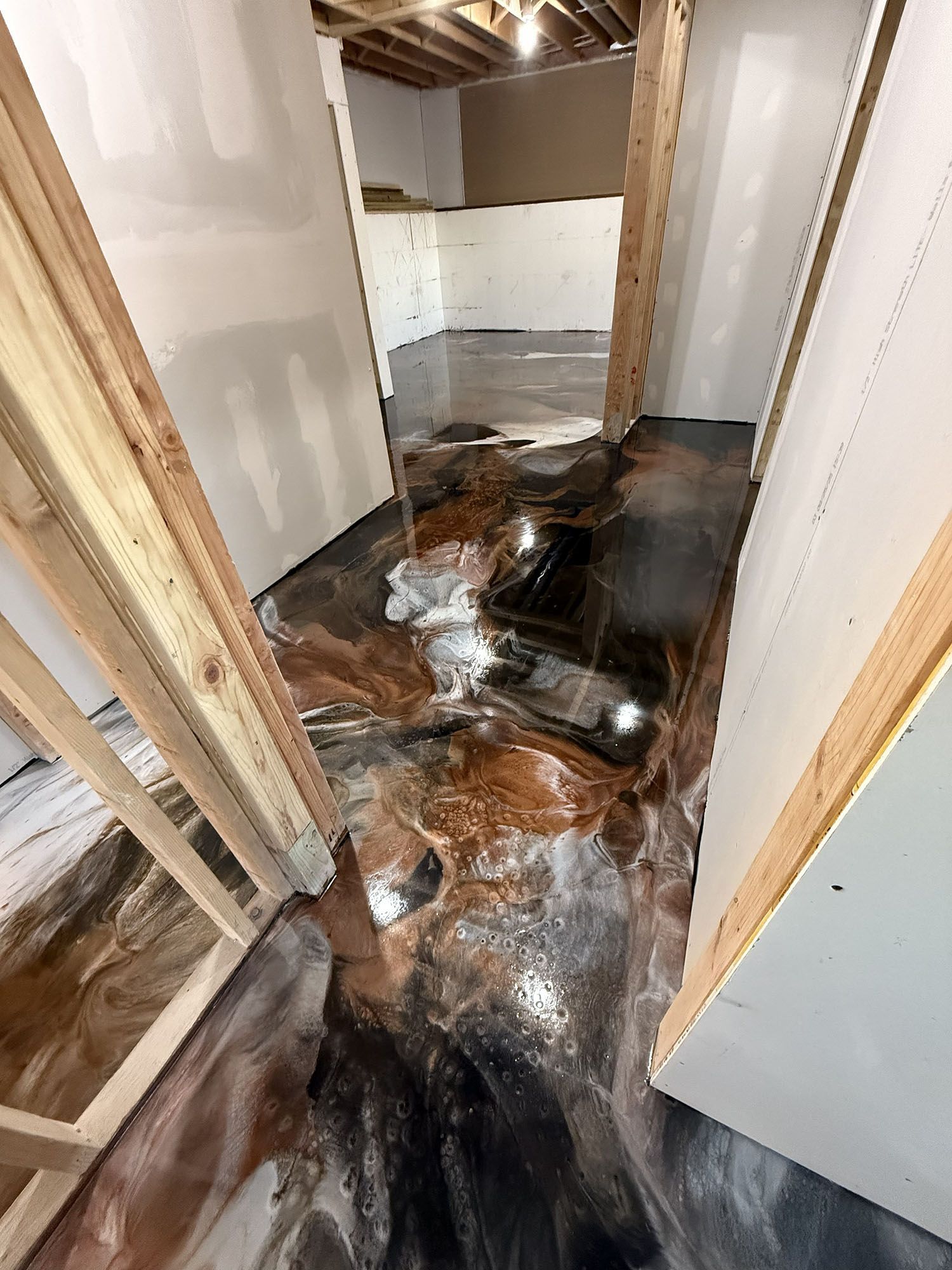 Water-damaged hallway with dark, glossy flooded flooring and exposed wall framing.