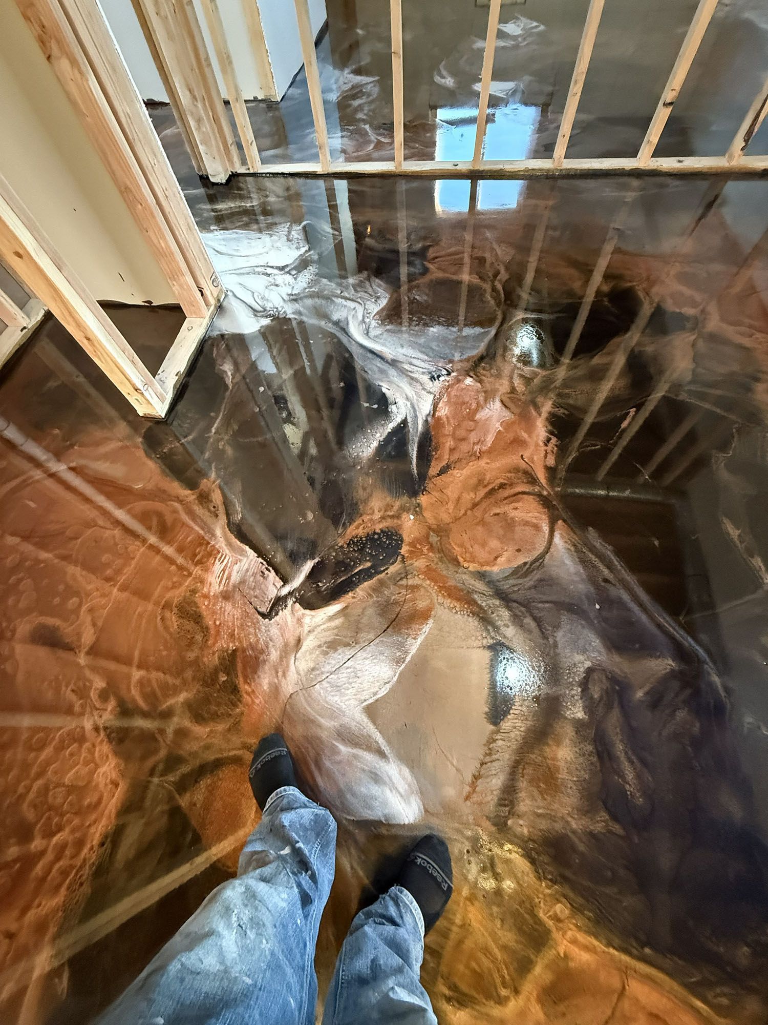 Person standing in a room with clear plastic sheeting over the floor and railing, viewed from above.