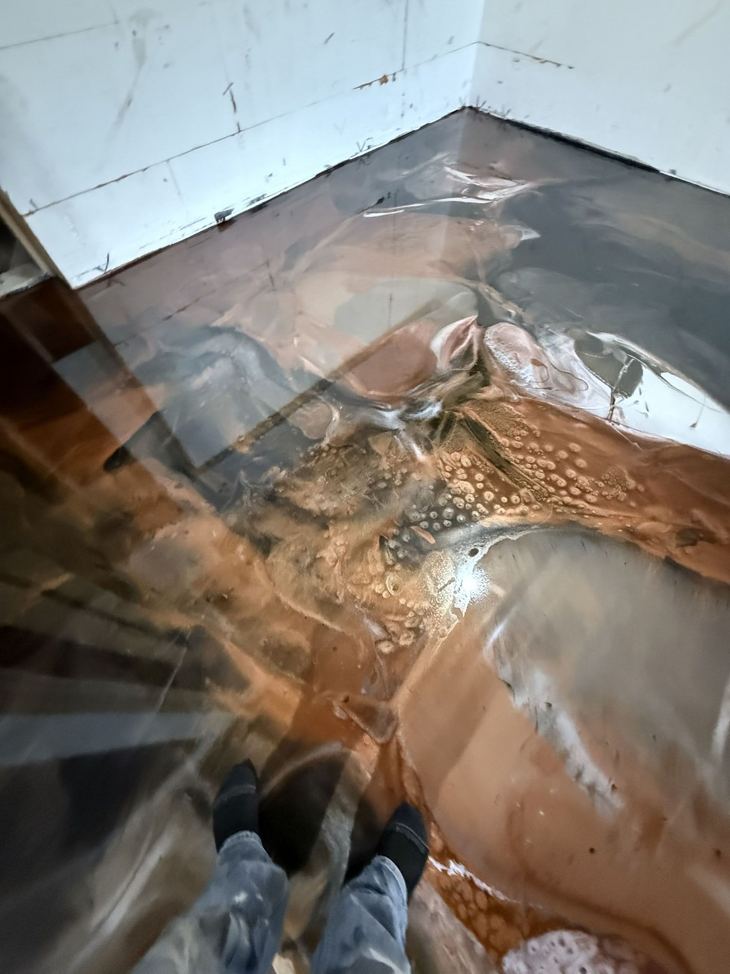Flooded room corner with muddy water and debris, seen from someone standing in the water.