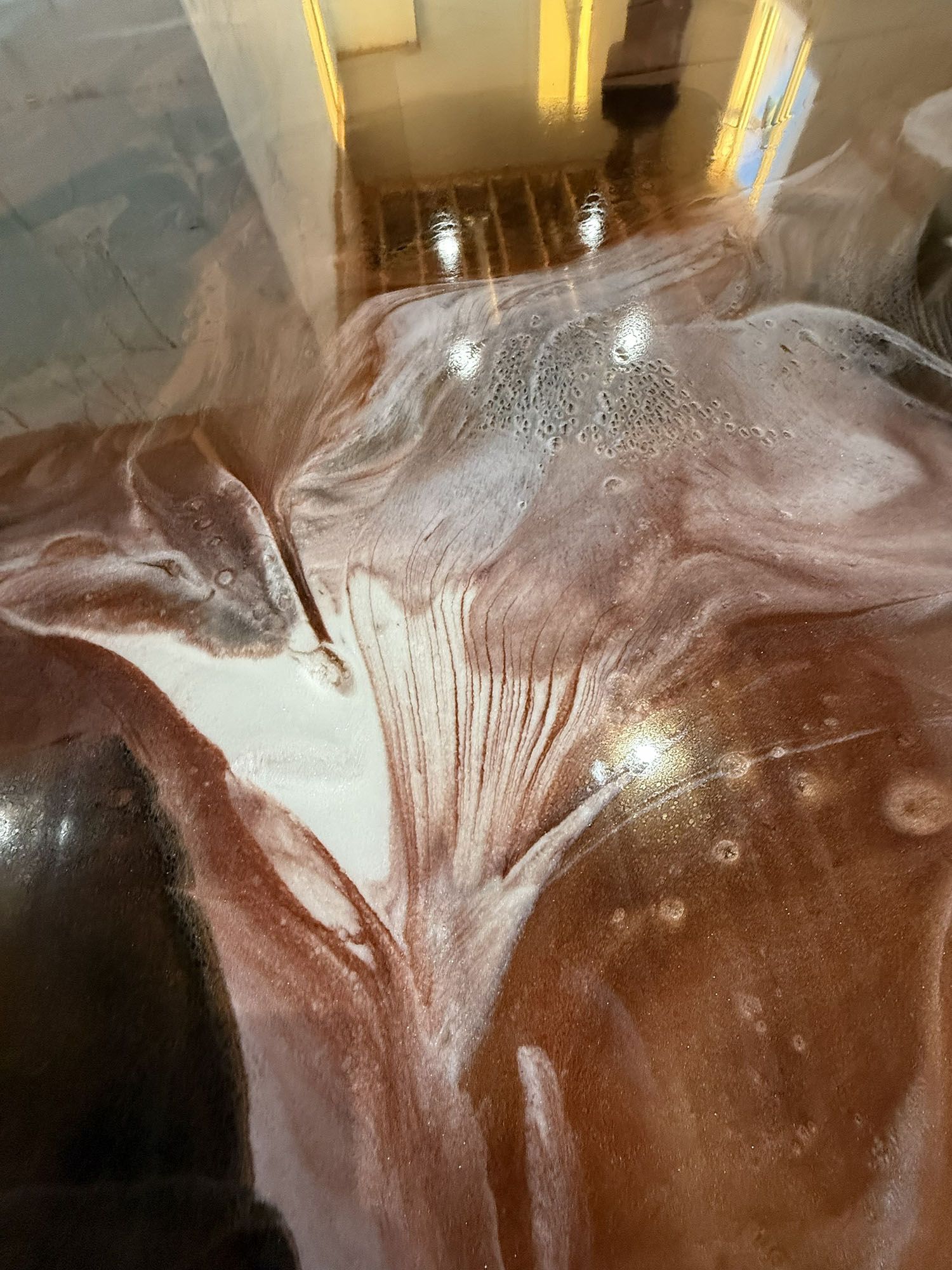 Shimmering white and brown marble-like surface with glossy reflections and abstract swirls.