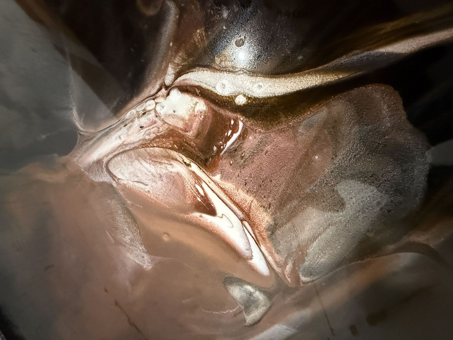 Close-up of abstract metallic folds in bronze, gold, and gray tones with soft reflections.