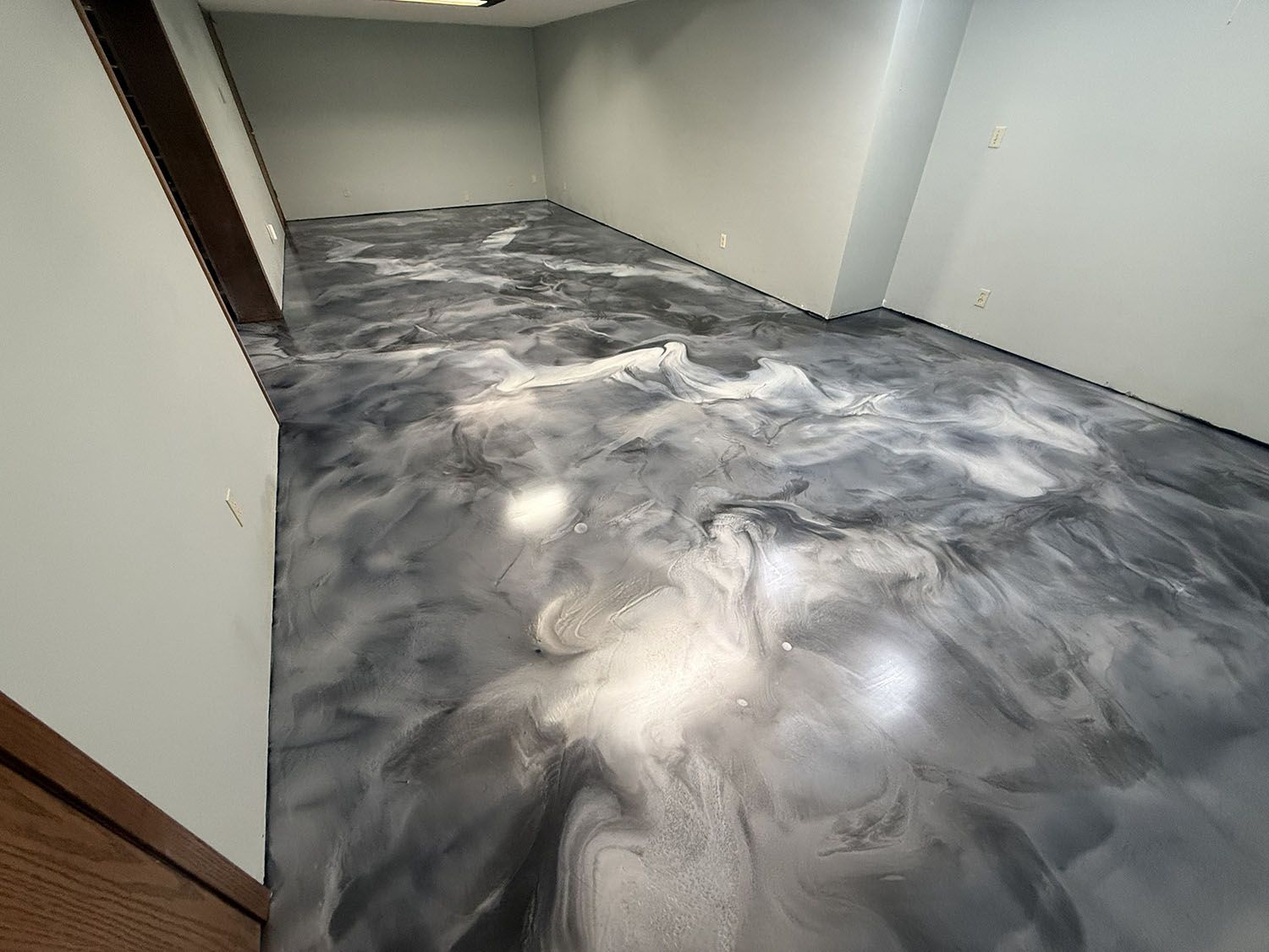 Empty hallway with a gray-and-white marbled floor and plain white walls.