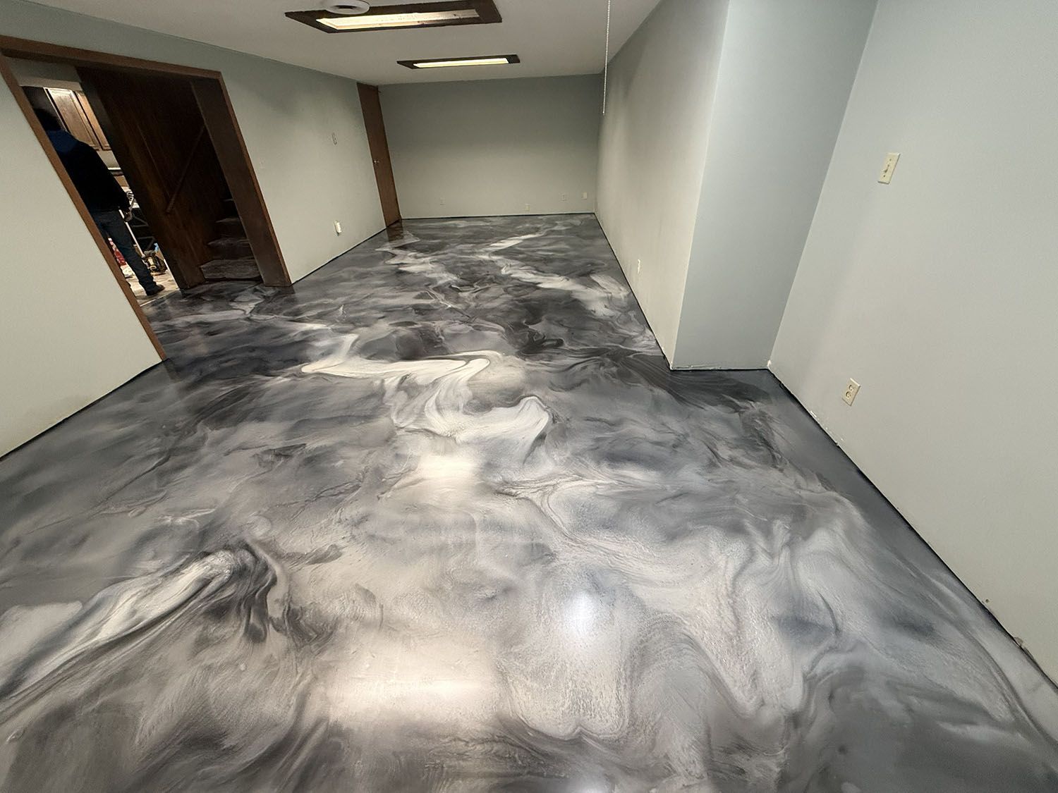 Empty office room with gray and white marbled carpet and white walls, viewed from a doorway.
