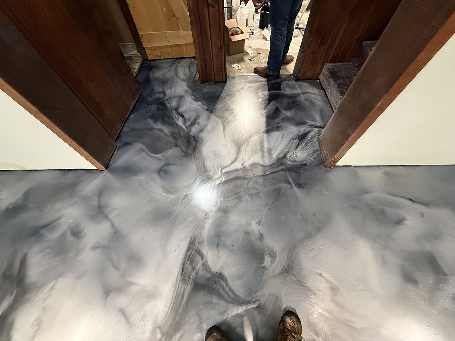 Marbled gray-and-white floor between wooden doorways, with a person visible at the far end.