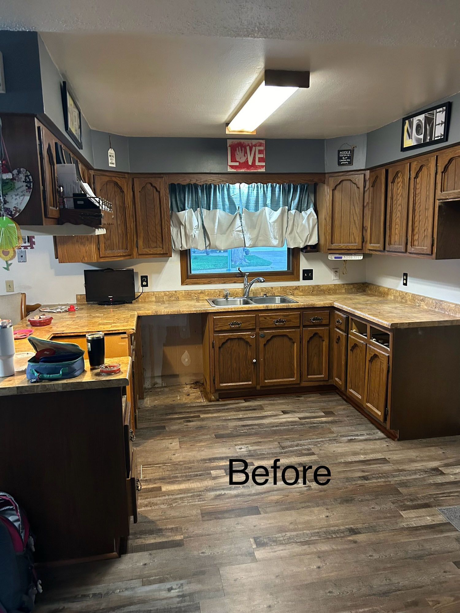 Before photo of a kitchen with wood cabinets, granite counters, and a window over the sink.