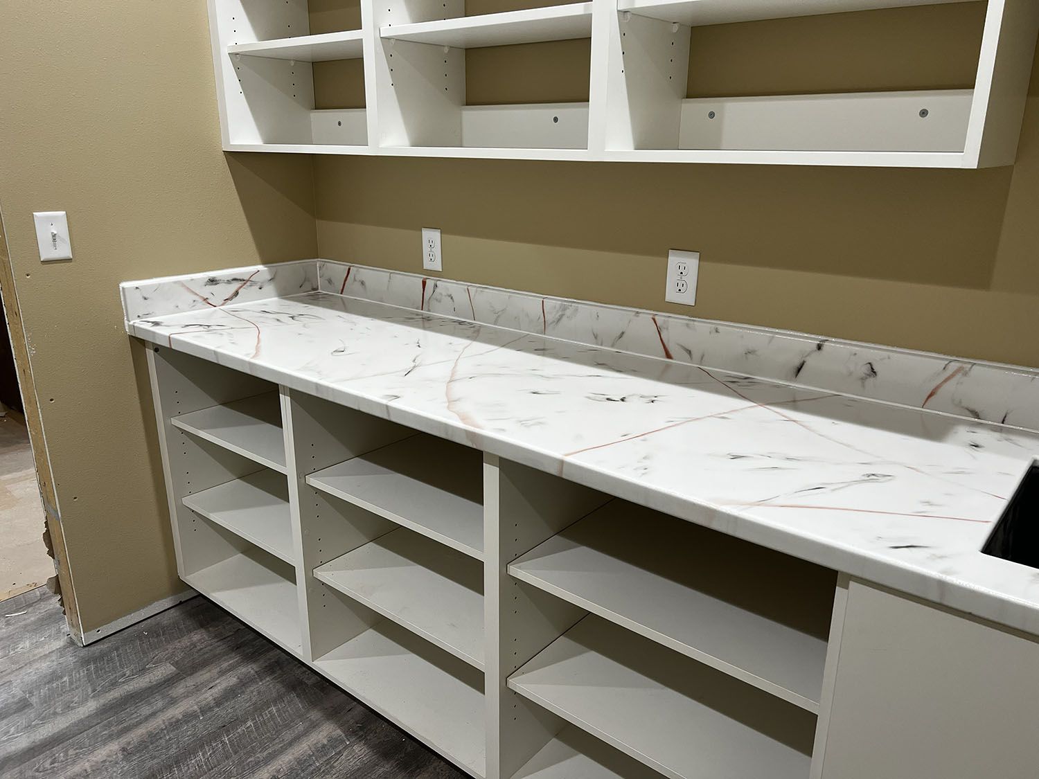 Built-in white cabinetry with marble-look countertop and open shelves in a beige room.