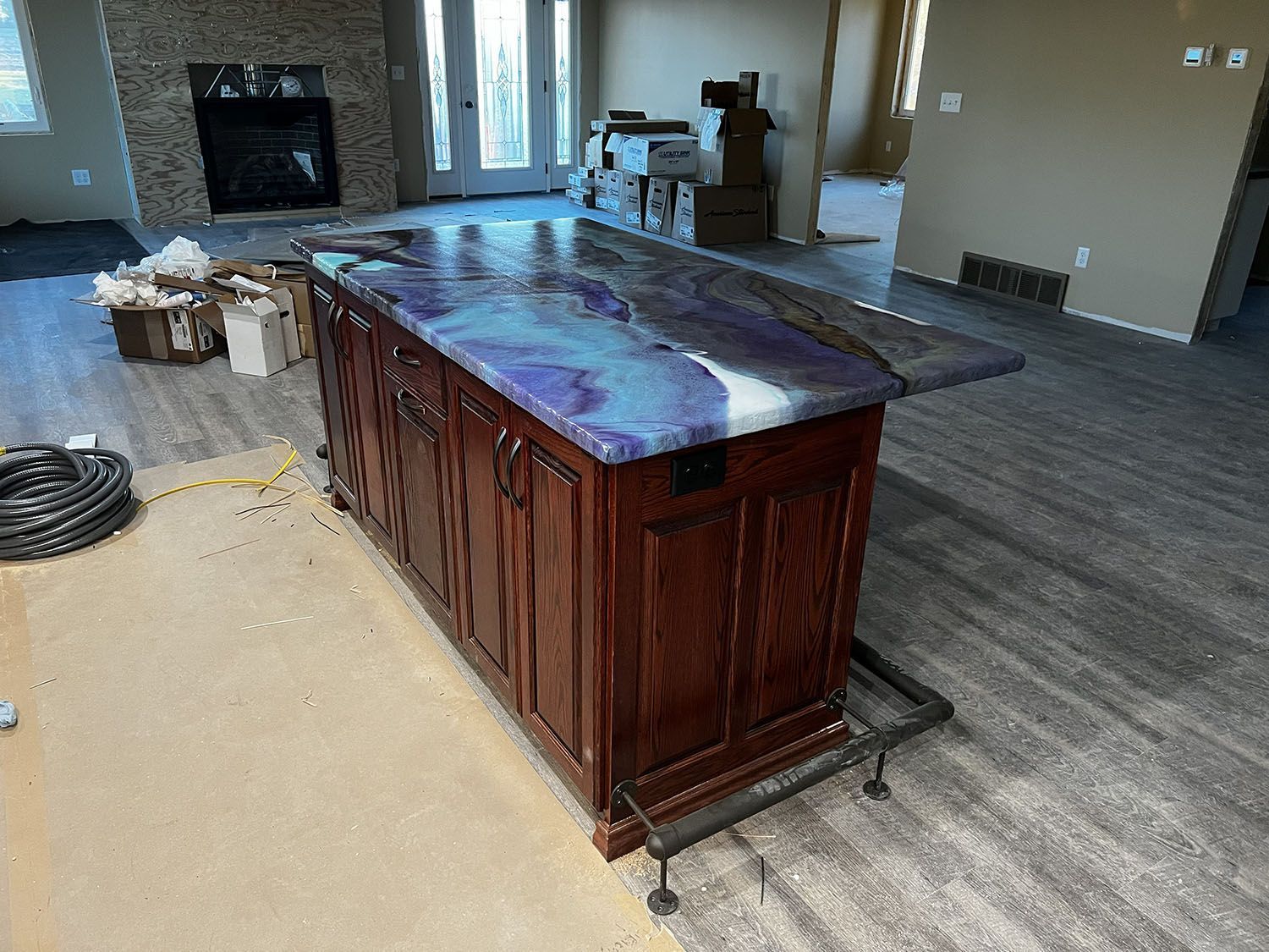Large wooden island with a purple countertop in a mostly empty room during renovation.