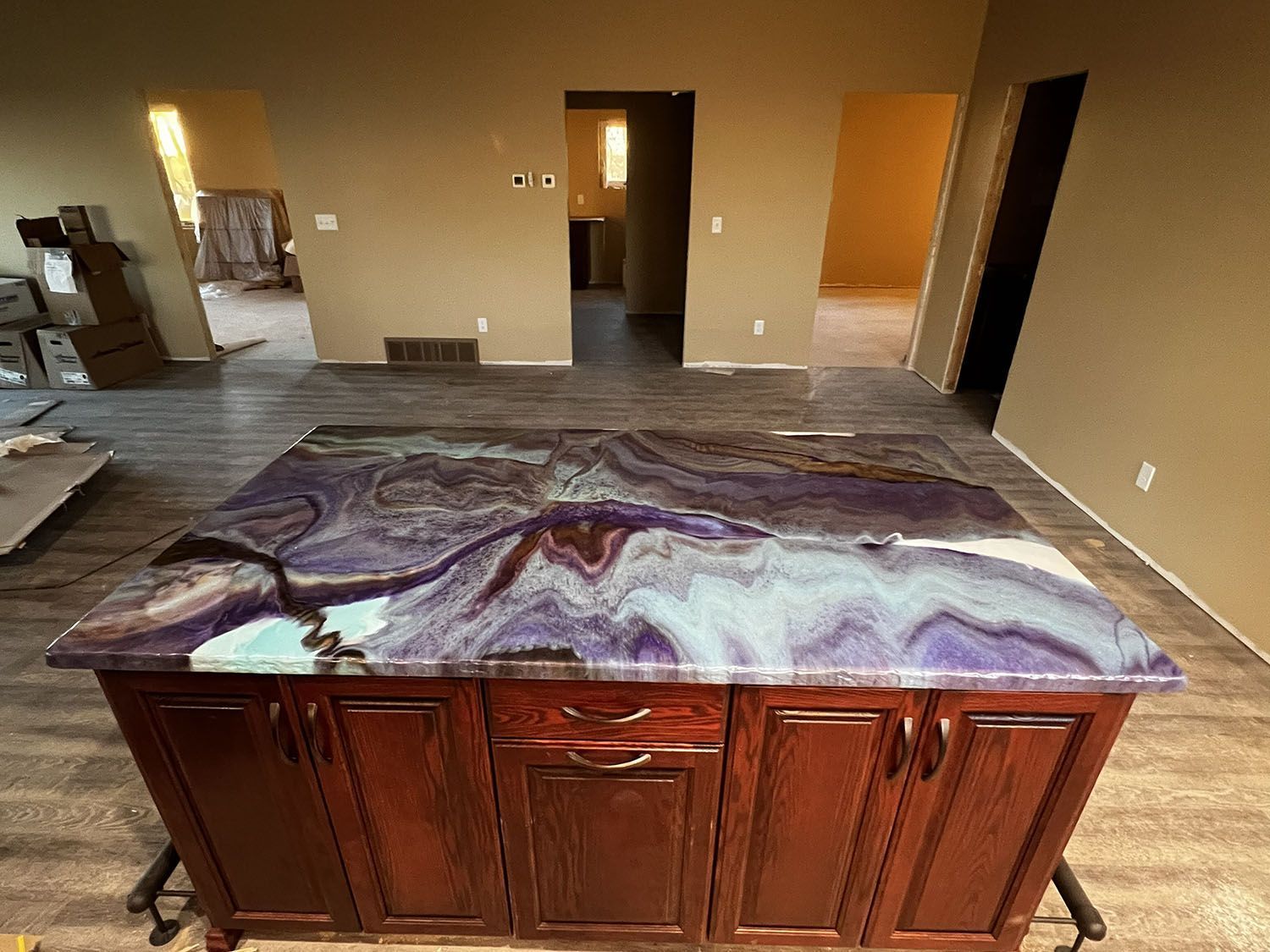 Large kitchen island with a marbled countertop in an unfurnished room under renovation.