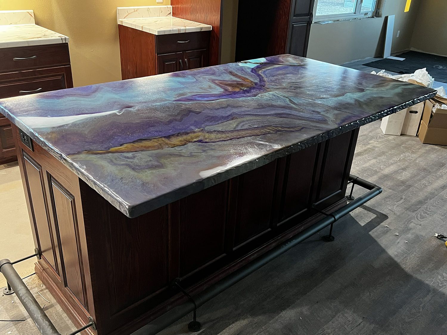 Large dark wood kitchen island with a glossy marbled stone countertop in a showroom.