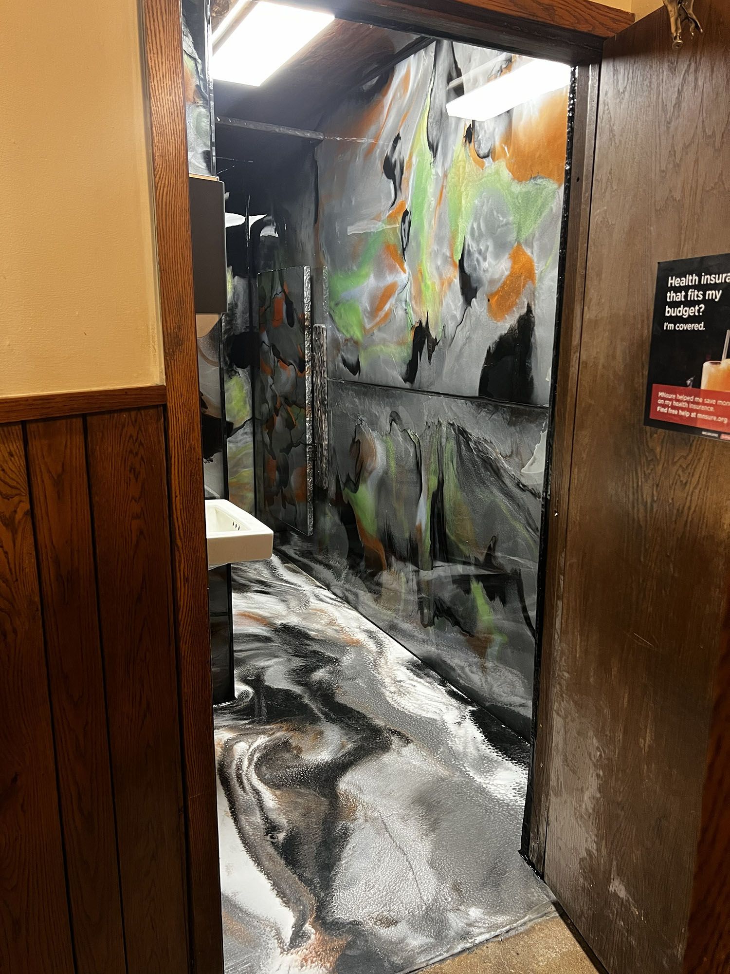 Narrow hallway with abstract black, white, gray, and orange mural walls and floor.