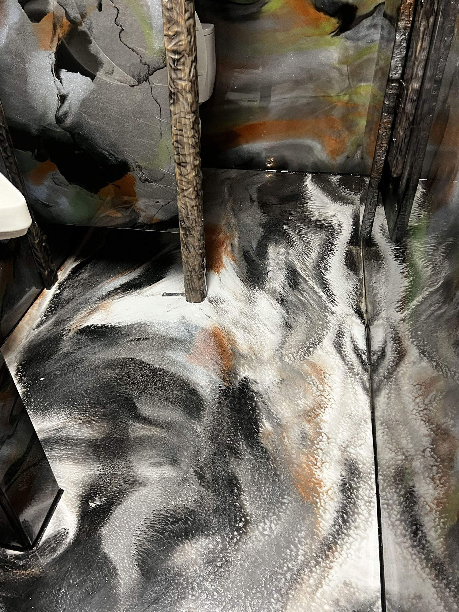 Abstract marbled fabric with black, white, gray, and orange swirls, viewed close up.