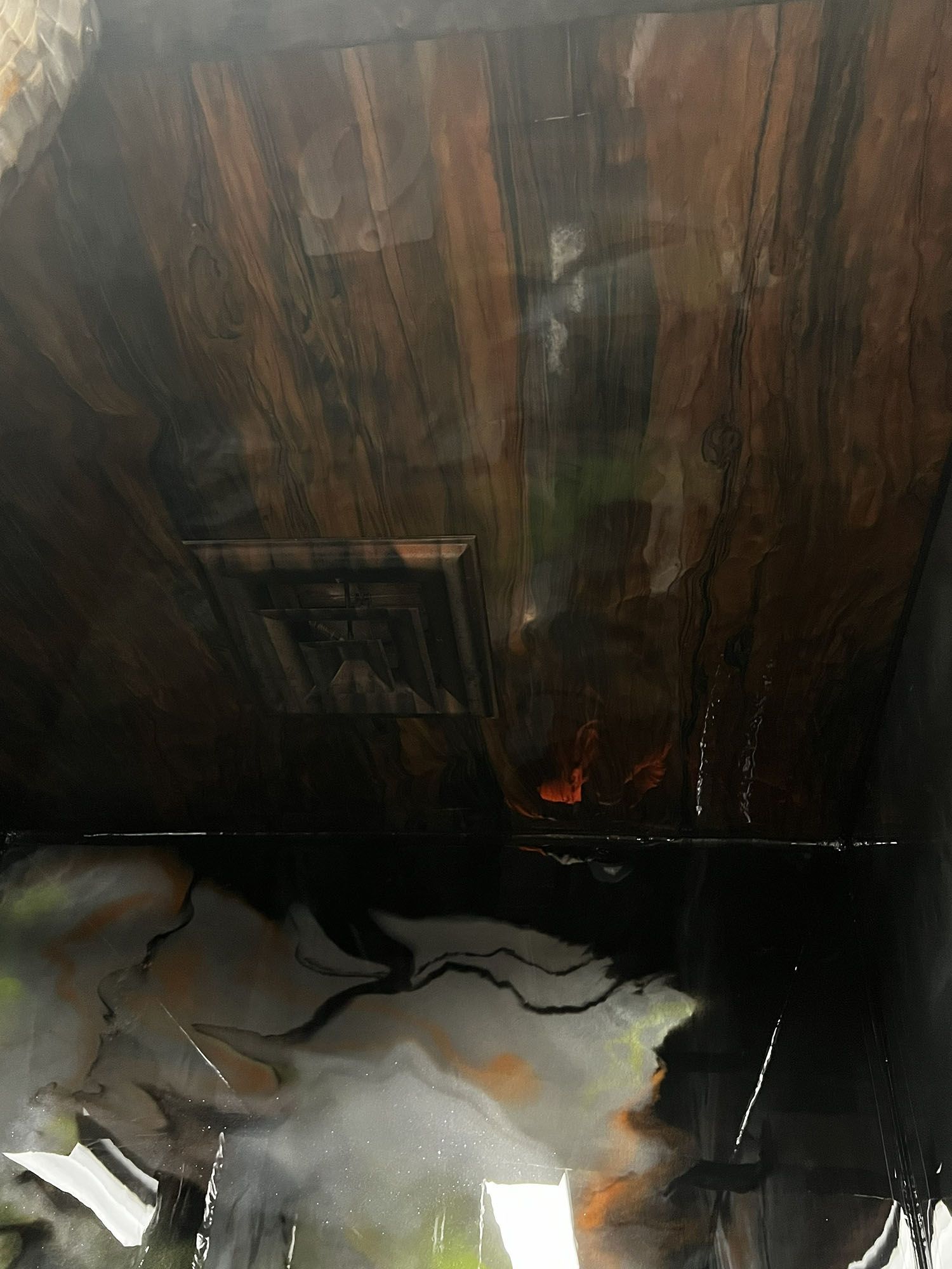 Burned room with charred wood wall, smoke stains, and debris on the floor.