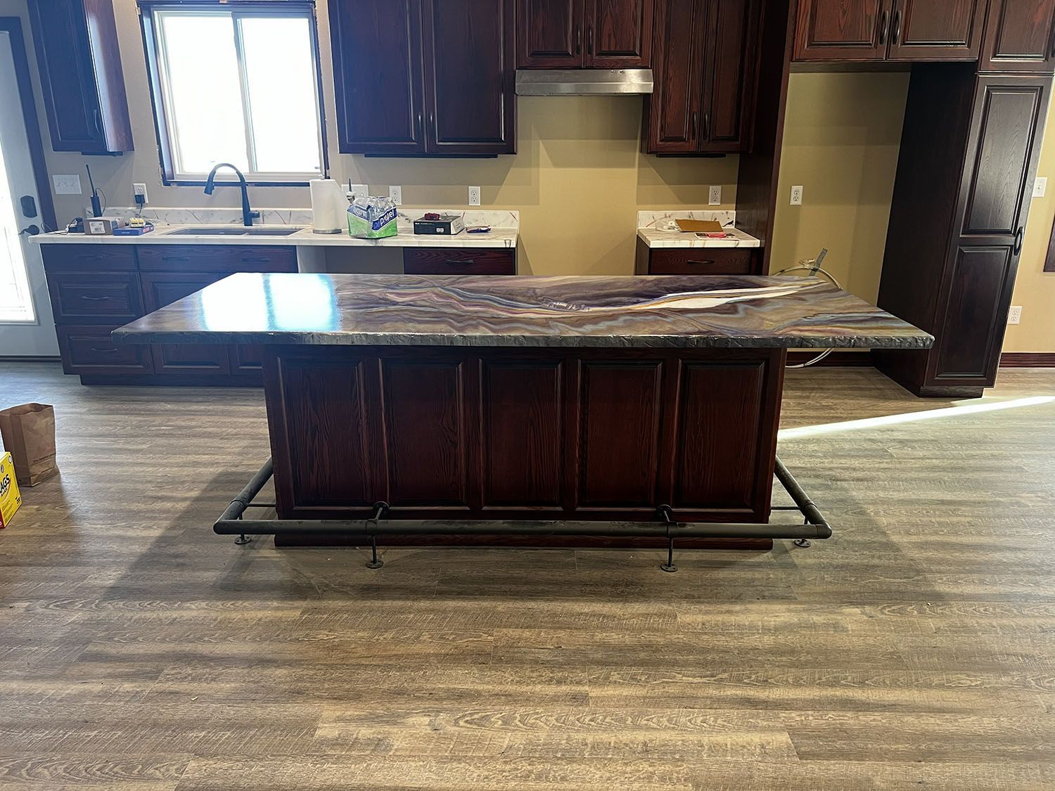 Kitchen with a large dark wood island and granite countertop in front of dark cabinets and a bright window.