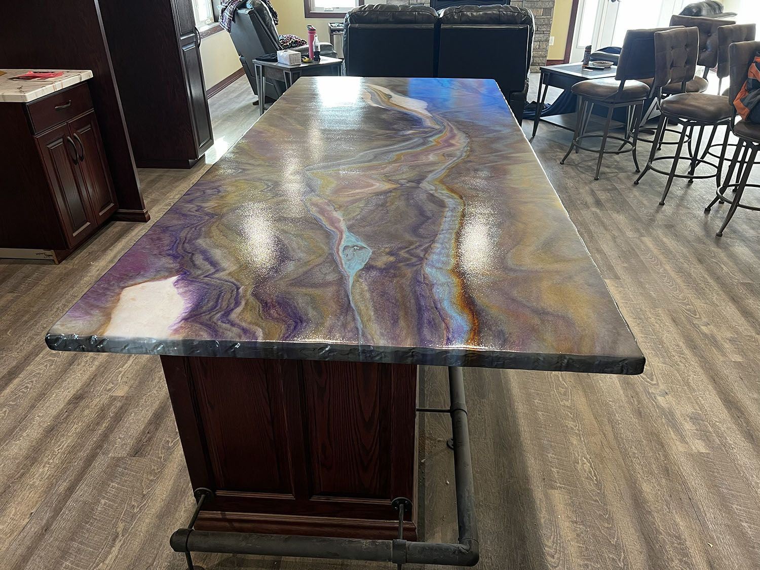 Large polished multicolored stone table in a showroom, with chairs and furniture in the background.