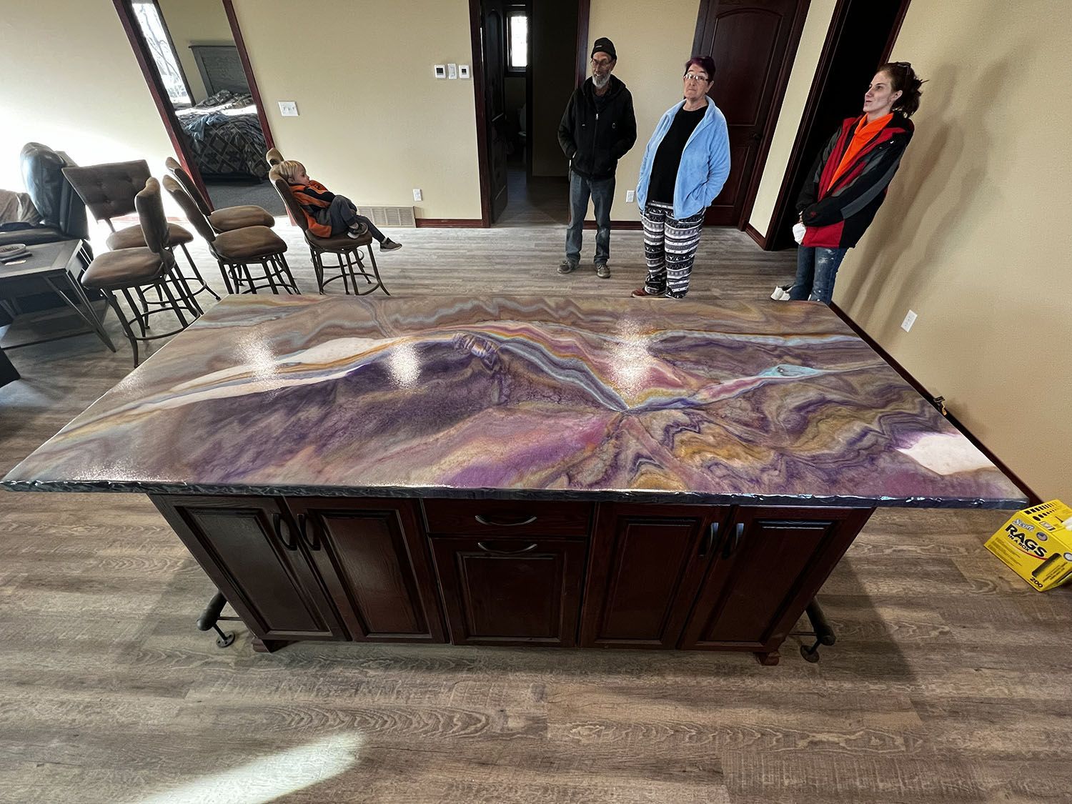 Large resin art dining table with a mountain-like design, displayed in a room with three people standing nearby.