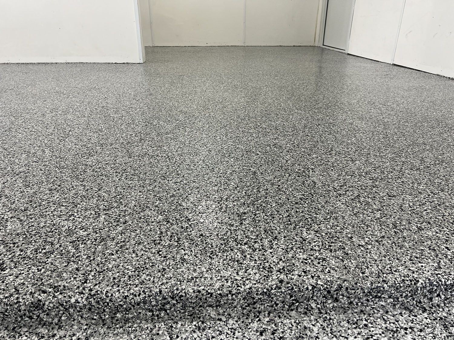 Speckled gray floor with a raised threshold near a white wall and door.