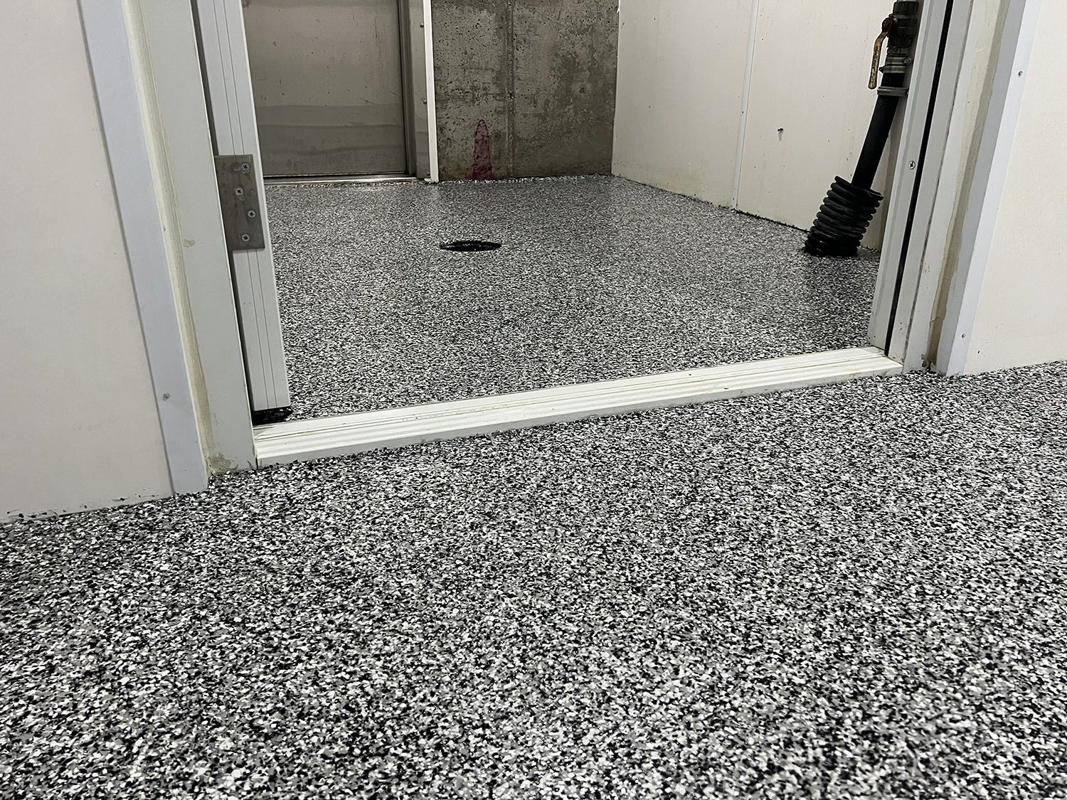 Speckled floor outside an elevator doorway in a hallway.