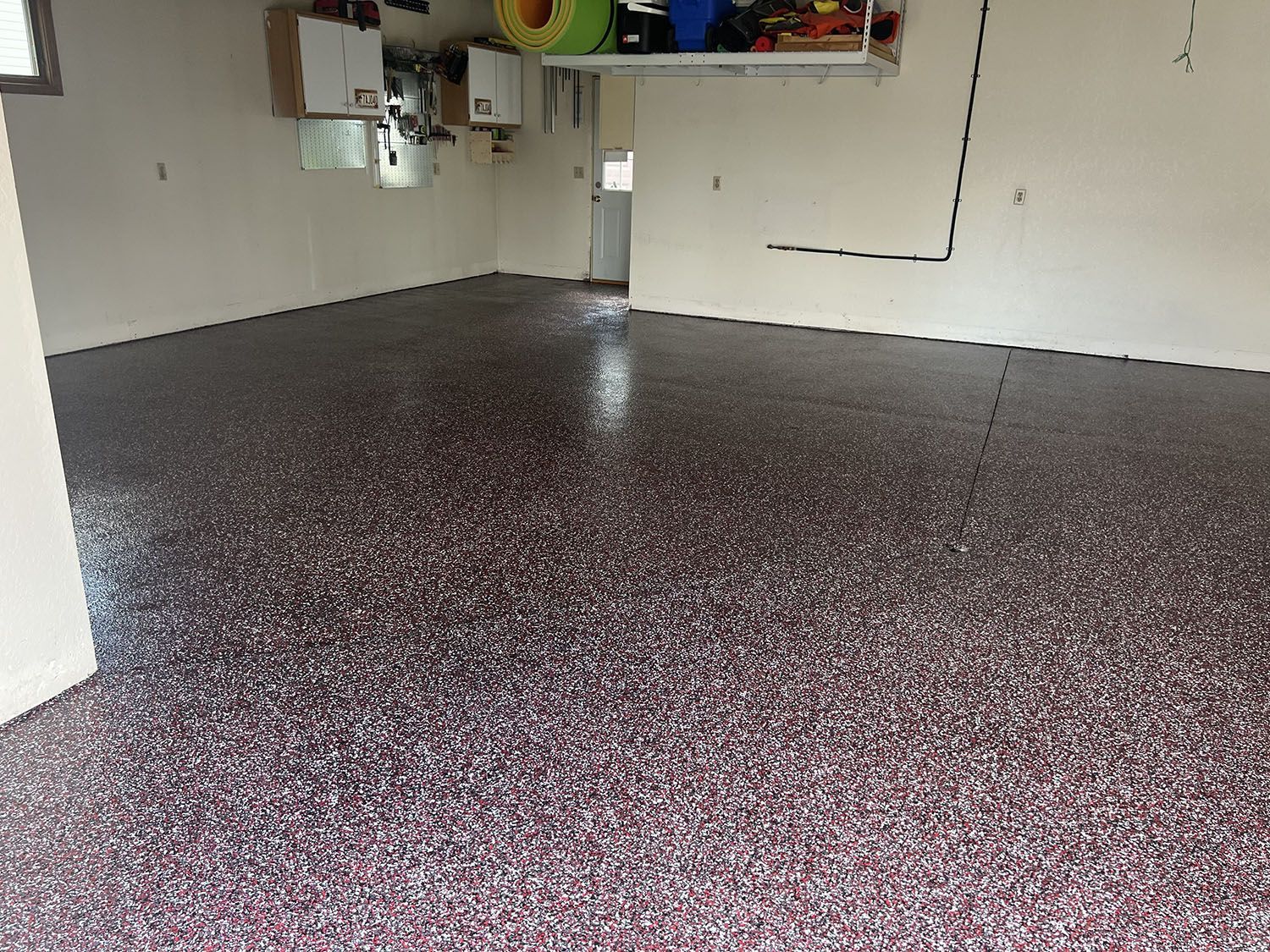 Empty garage with a speckled epoxy floor and storage shelves along the walls.