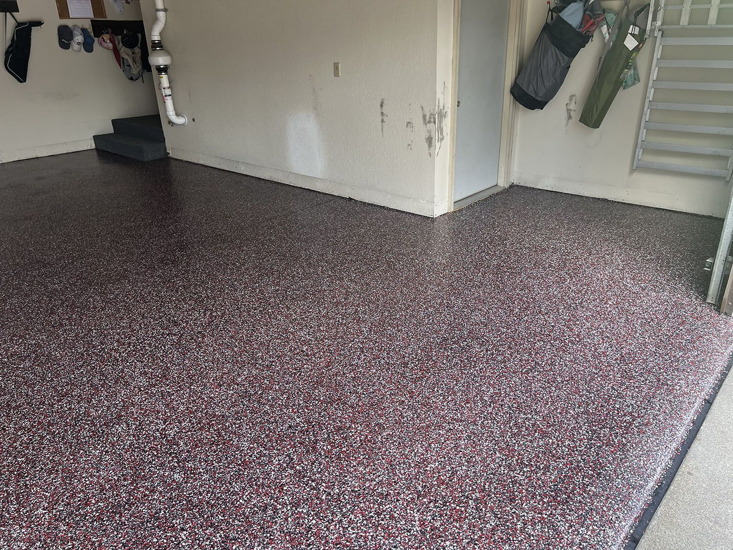 Garage with a speckled epoxy floor, white walls, and stairs along the right side.