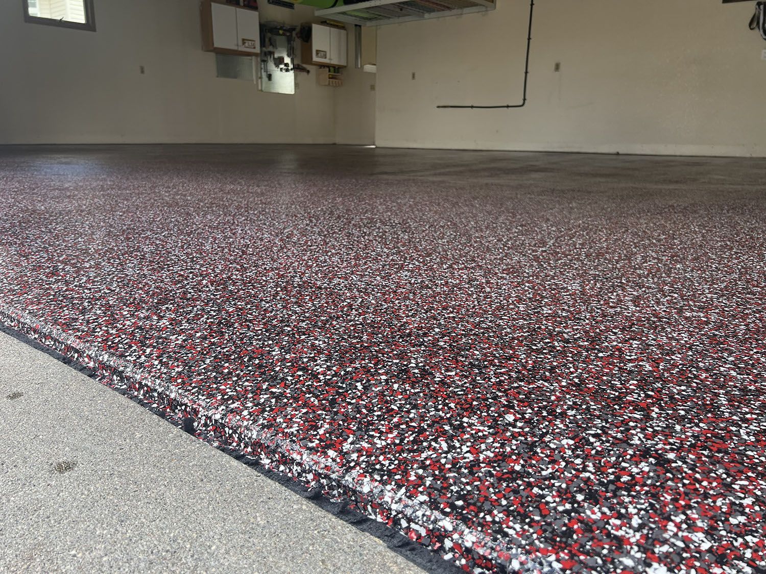Sparkling red, white, and black epoxy floor in an indoor garage or workshop.