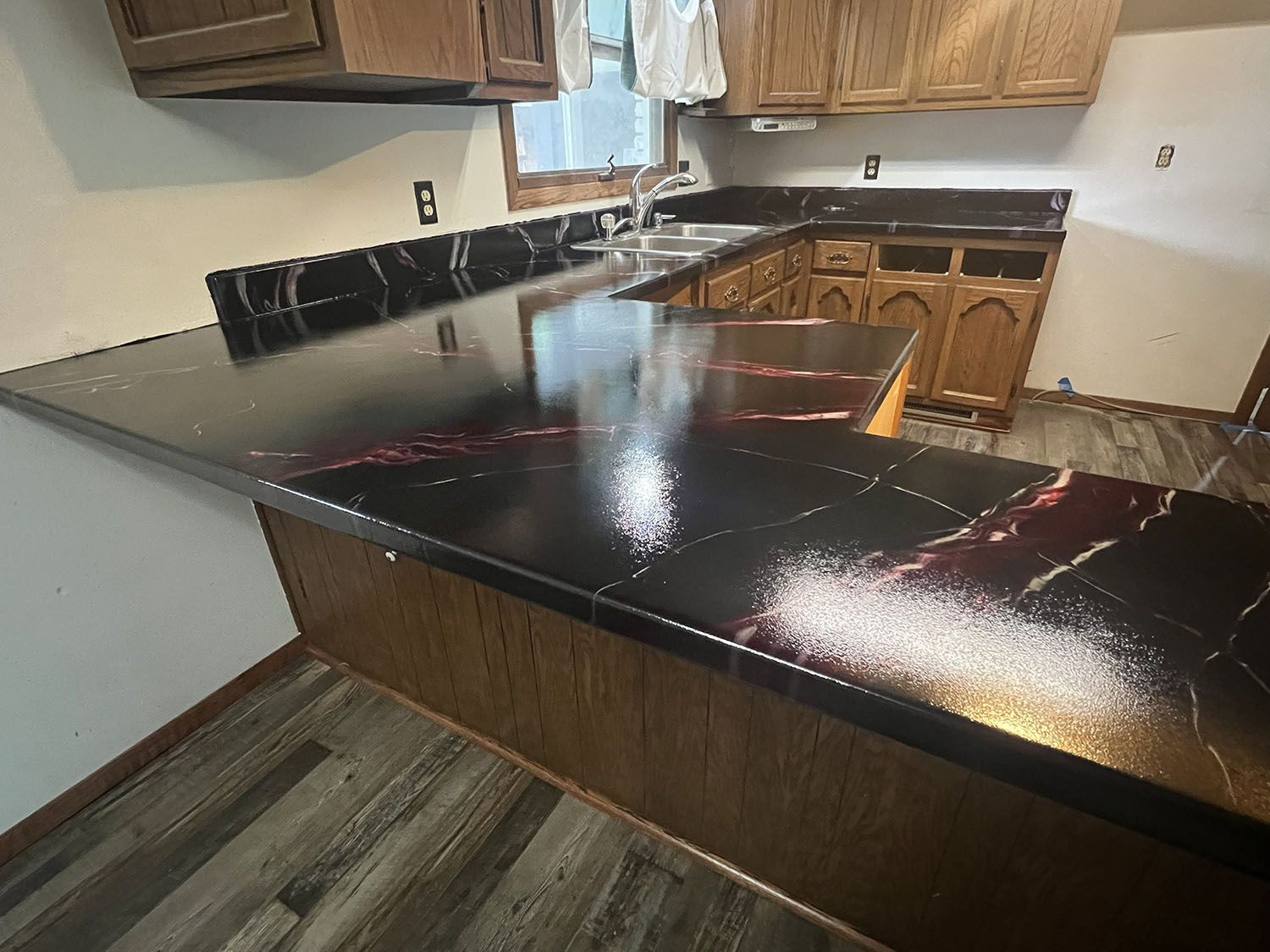 Kitchen with glossy black granite countertops and wooden cabinets in a corner layout.