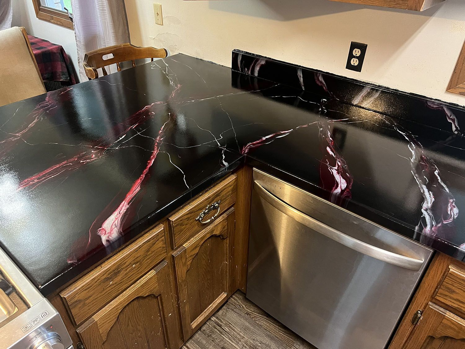 Black marble-look kitchen countertop with pink veining and stainless steel dishwasher beneath.
