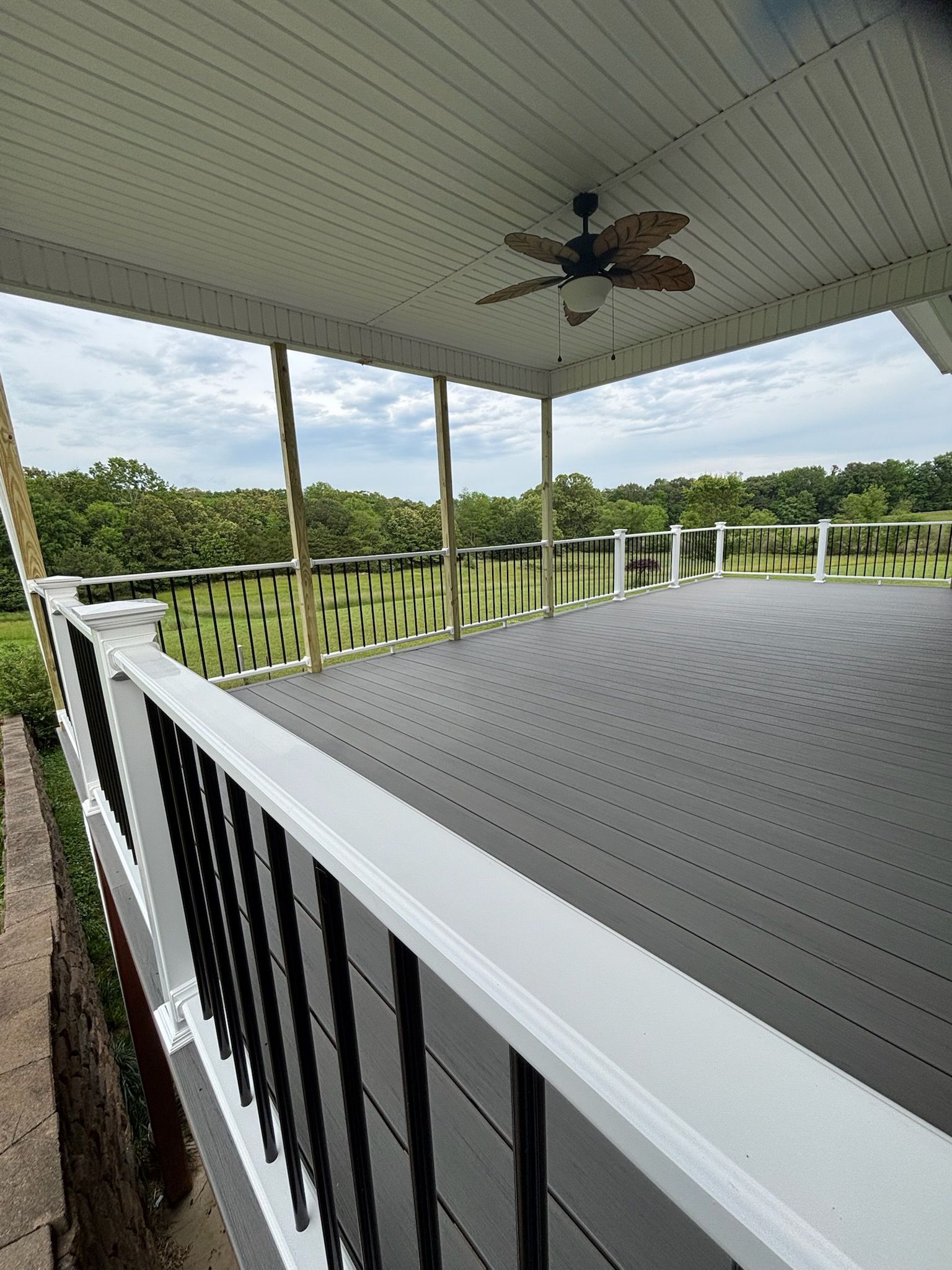 A large porch with a ceiling fan and a view of a golf course.