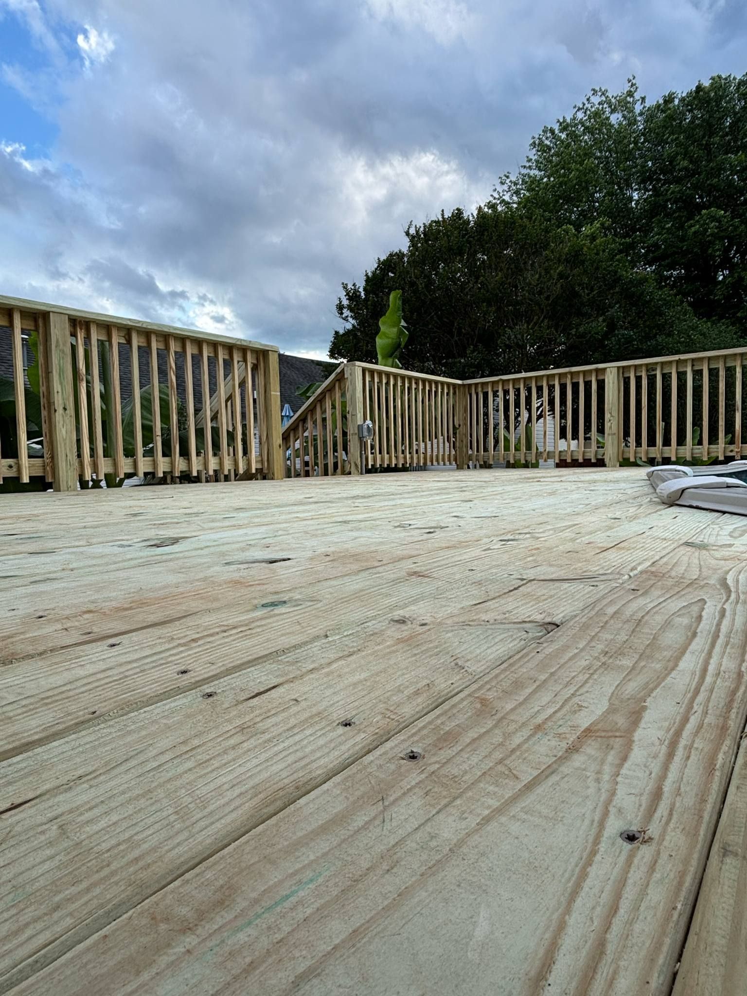 A wooden deck with a railing and trees in the background