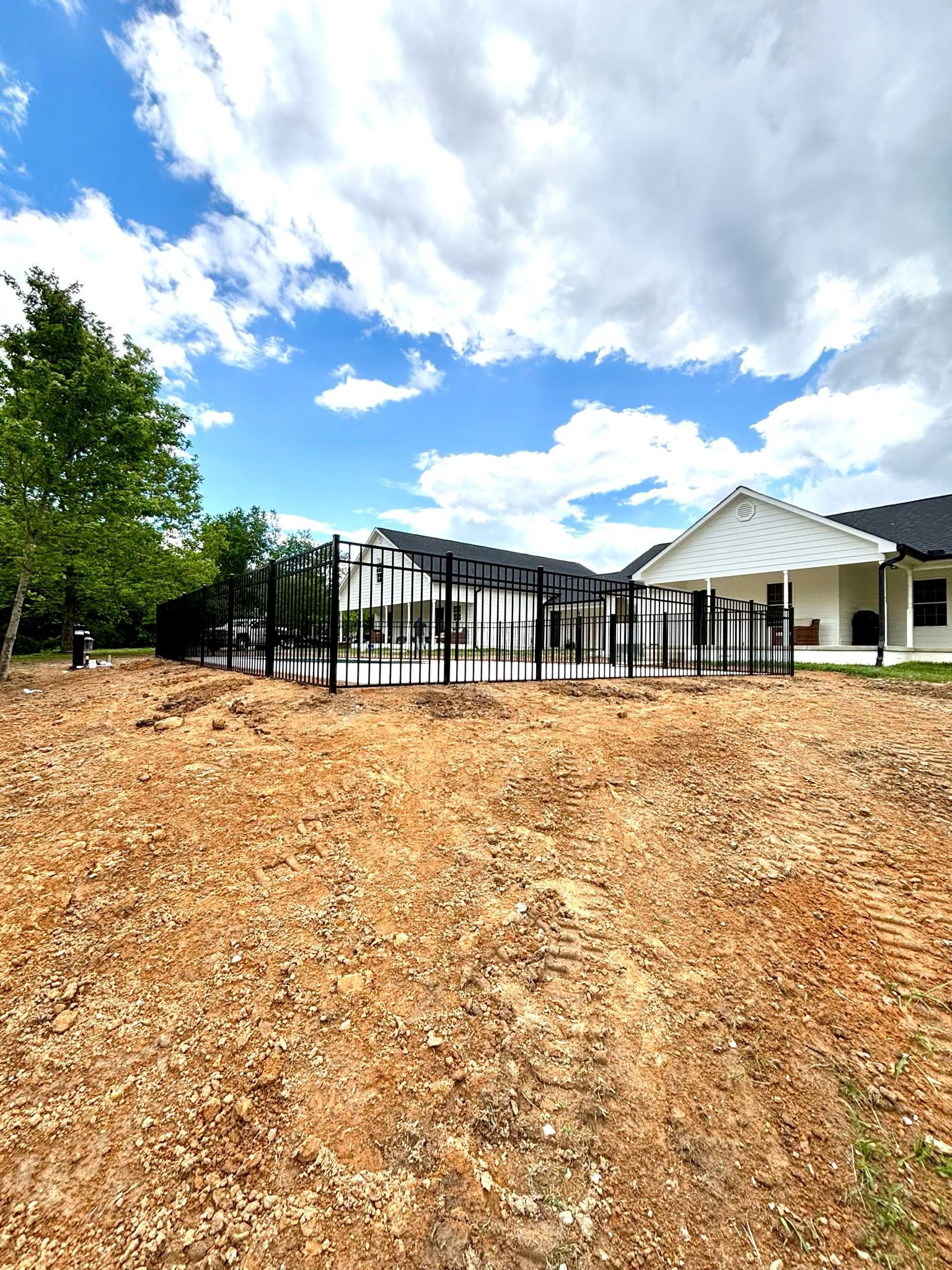 A large yard with a house in the background and a fence in the foreground.