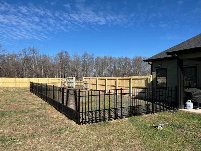 A backyard with a black fence and wooden fences.